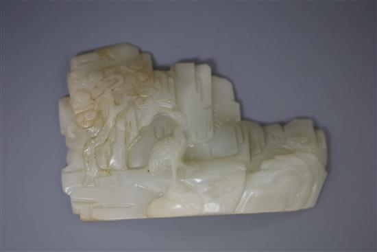 A Chinese pale celadon jade landscape carving, 19th century, W. 9cm, H. 6cm, millet and rockwork carved wood stand